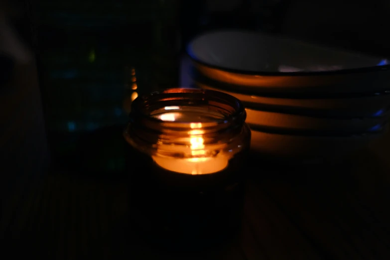 a candle sits next to plates in the dark