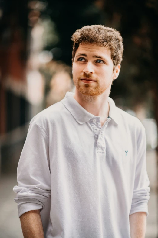 a young man with a mustache standing by himself