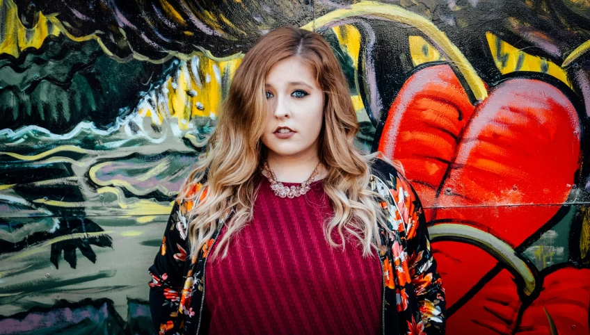 a person standing in front of graffiti covered wall