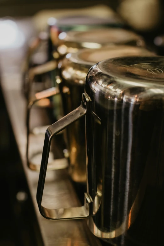 a row of metal coffee cups sitting on a counter