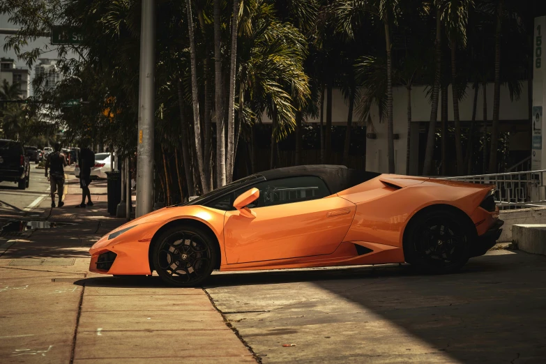 an orange sports car parked on a sidewalk