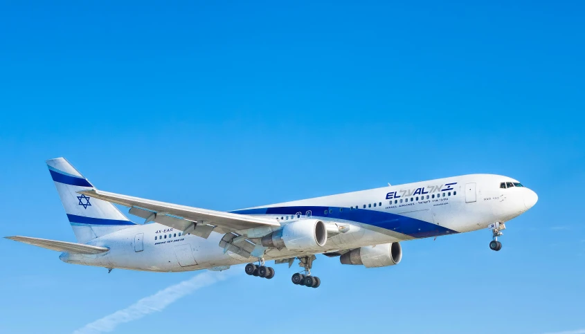 a commercial airplane flies in a blue sky