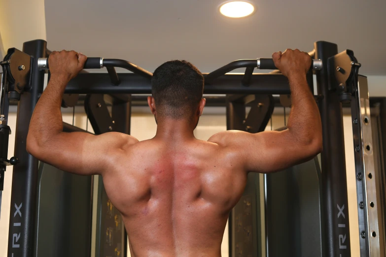 a bodybuilding athlete working his back on a pull up machine