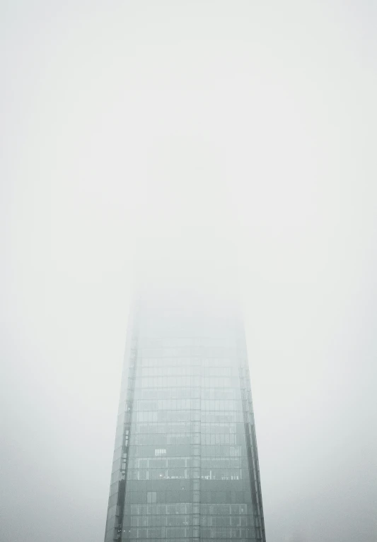 a tall skyscr towering over a city on a foggy day