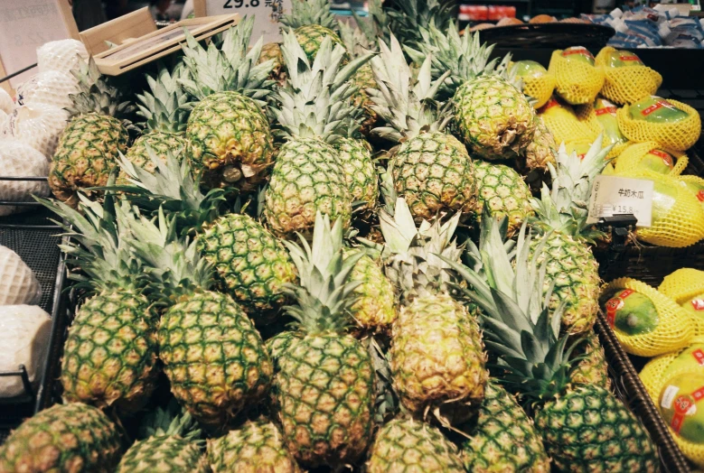 piles of pineapples on display at a grocery store