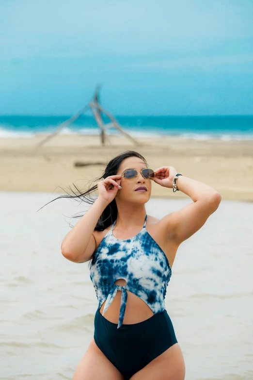 a young woman is standing on the beach wearing a one piece swimsuit