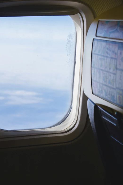 there is an airplane window that is very close to the sky