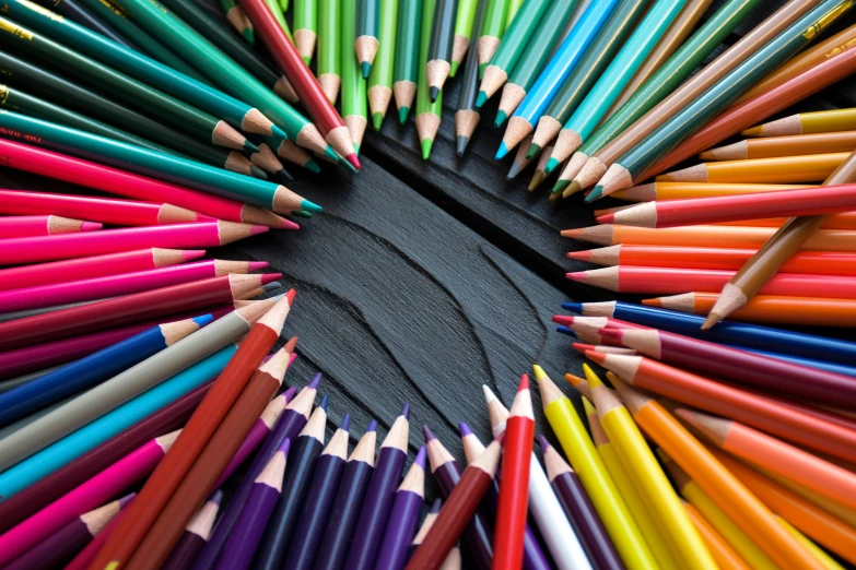 colored pencils arranged in a circle with a black background