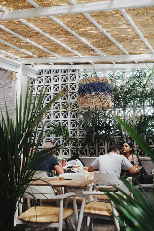 people sitting at outdoor seating under a pergolated roof