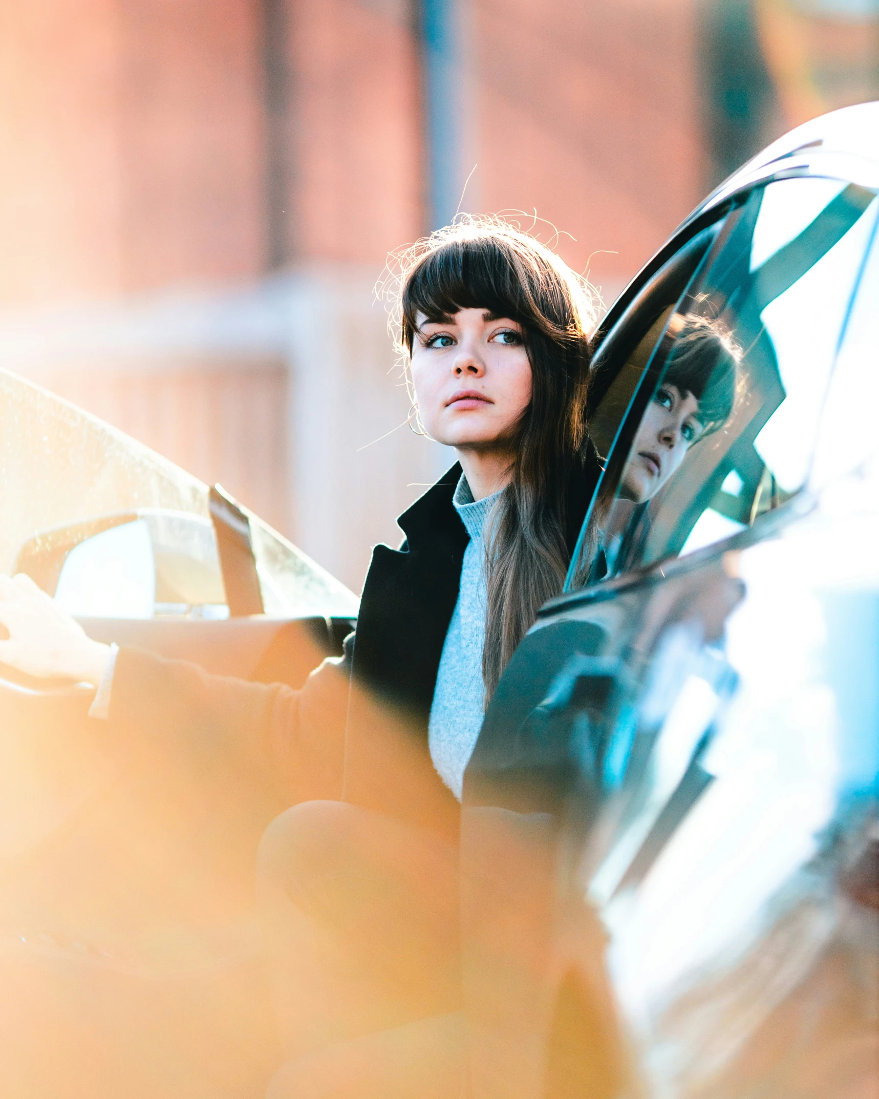 two women are standing by a car and holding an umbrella