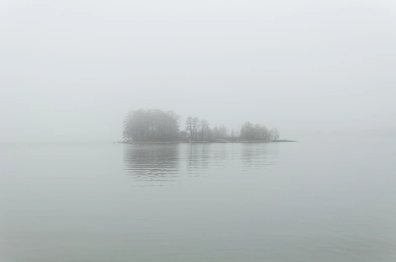 foggy day and the lone island on a body of water