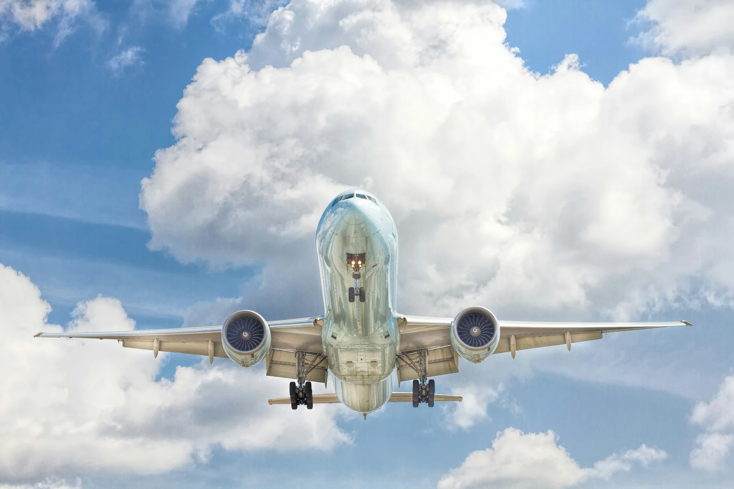 a jumbo jet flying over the clouds on a partly cloudy day