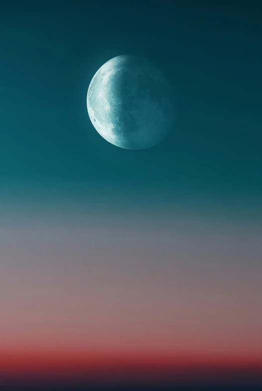 the moon rising over a twilight horizon at dusk