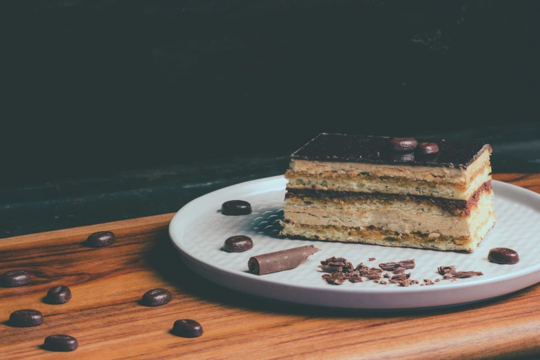 three layers cake on a white plate, with chocolate and milk pieces scattered about