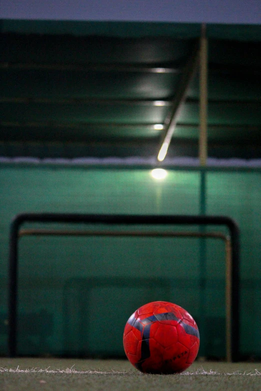 a soccer ball sitting on the ground with dark green and red background