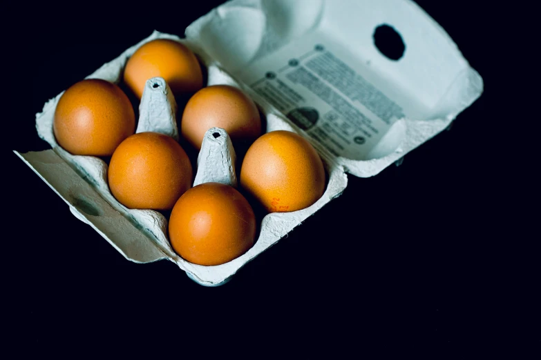 dozen eggs in an egg carton on black background