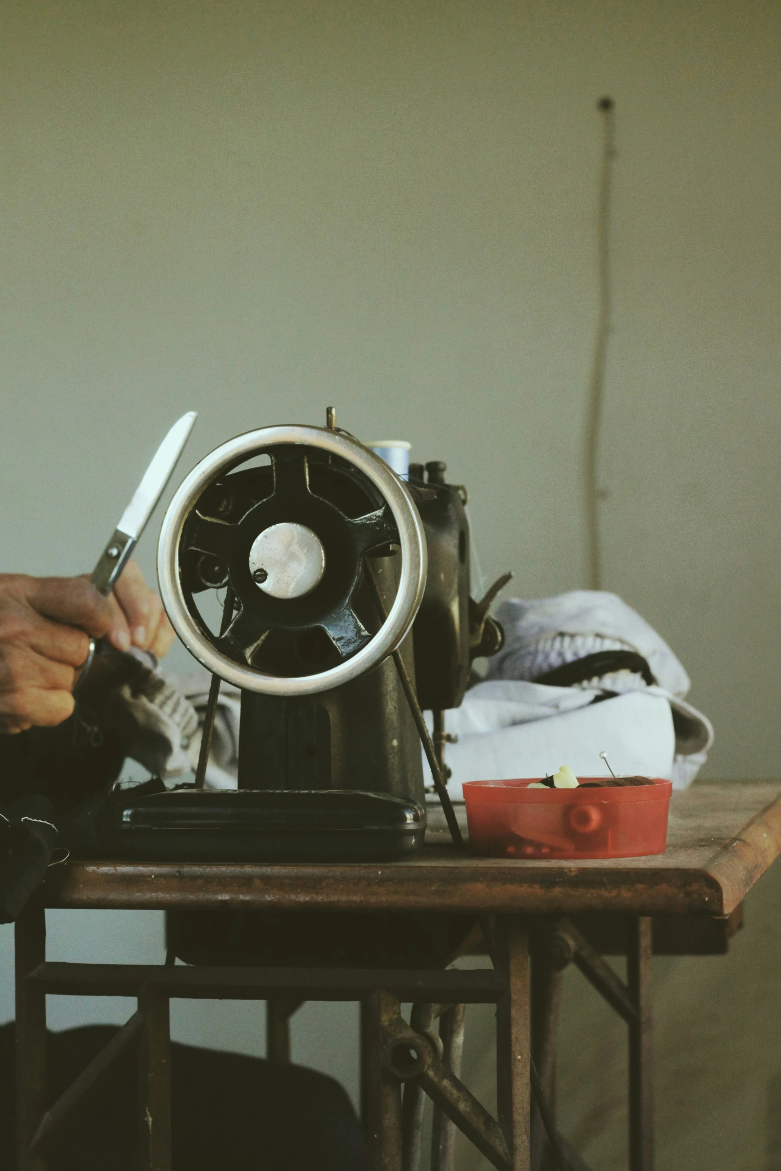 a close up of a person holding scissors and pointing to a sewing machine