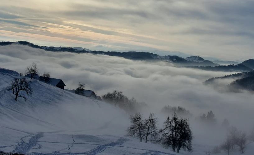 a very tall hill covered in fog on top of a snow covered slope