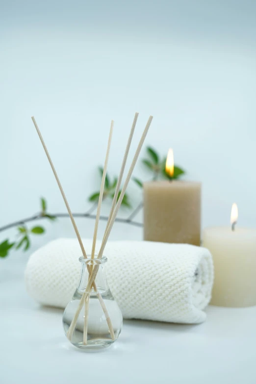 candles are arranged beside a vase containing reeds