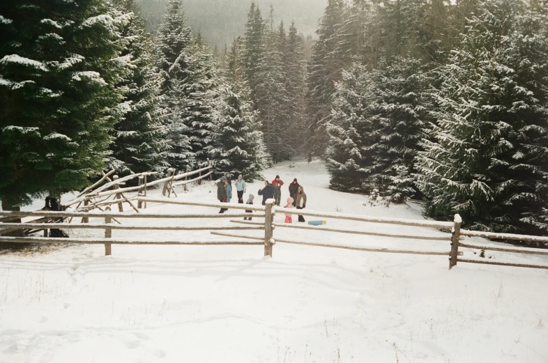 a group of people are standing in the snow near a gate