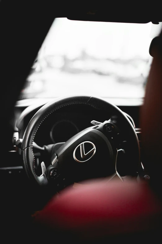 a steering wheel of a car with other cars parked