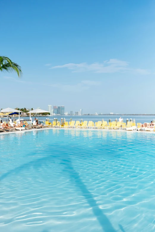 people sitting at tables and chairs by a large pool