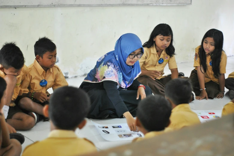 several children in yellow shirts are around a white table