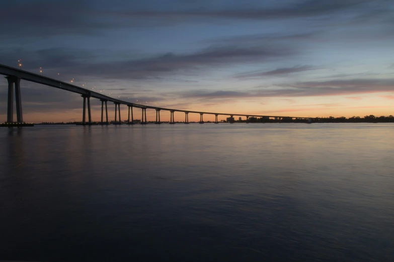 an empty bridge on the water at dusk