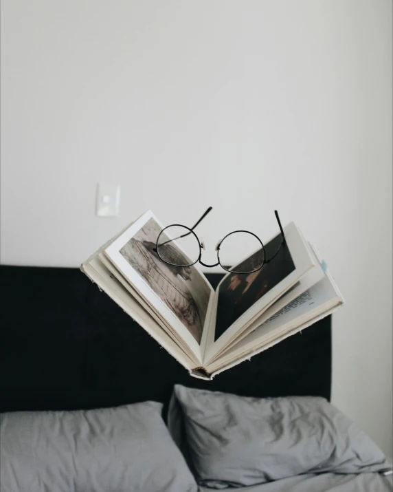 a book opened with some glasses and a pillow in the bed