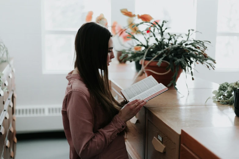 a woman is holding an open book and looking into the drawer