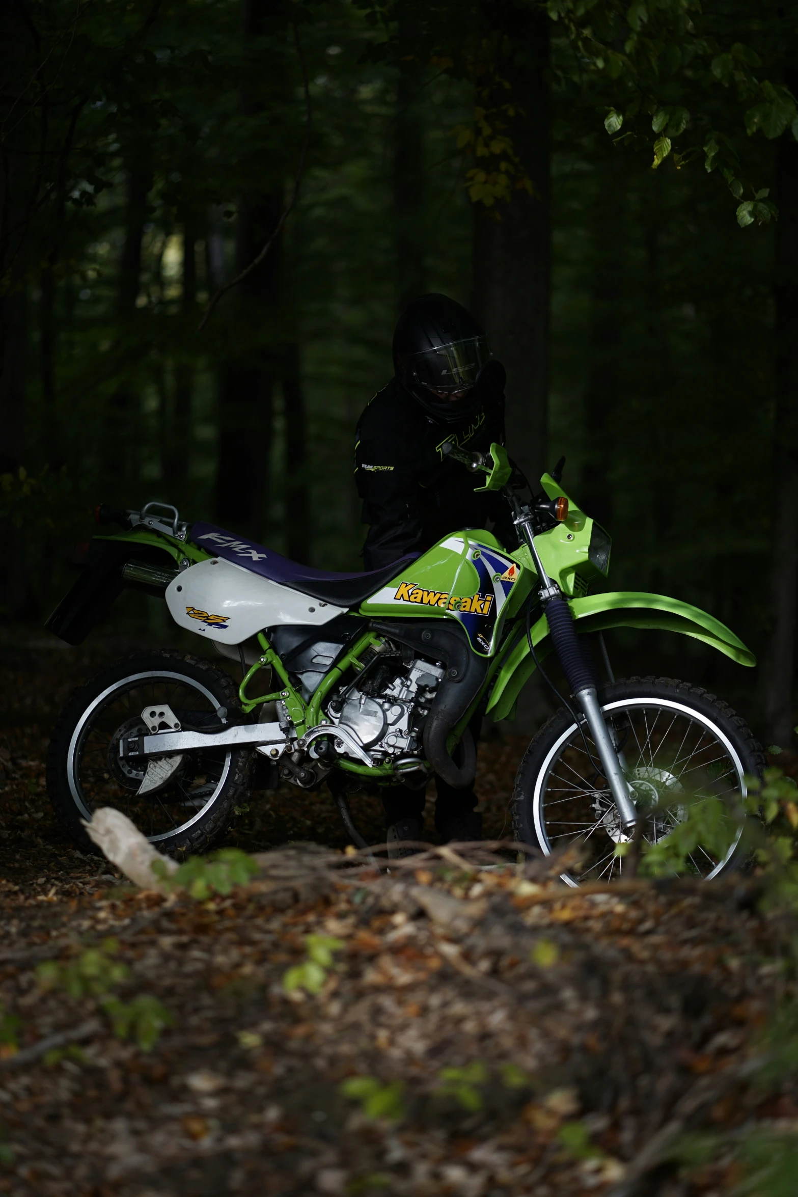 a man wearing black standing next to a motorbike