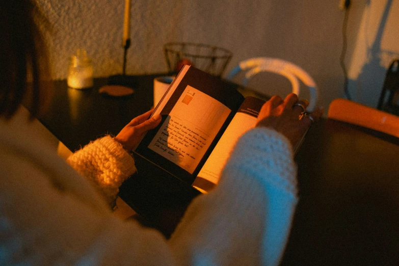 person holding up a book in a dark room