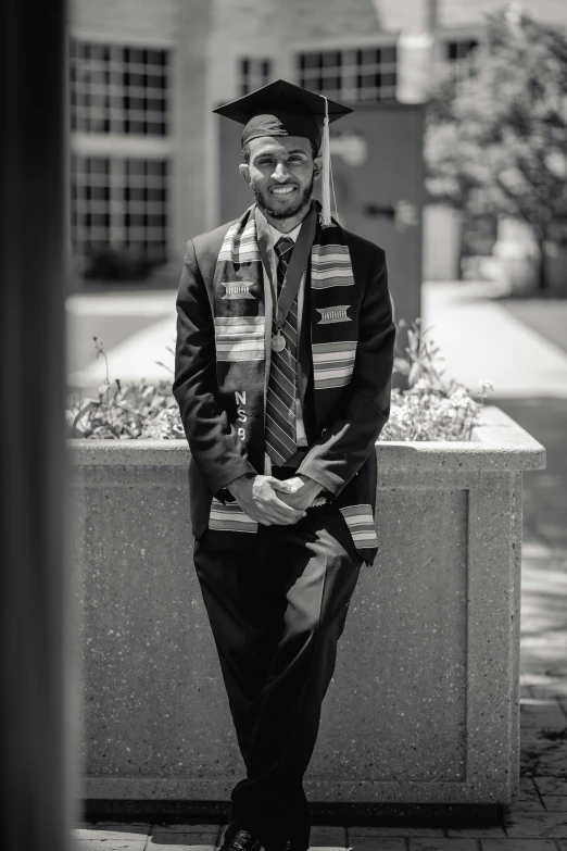 a man wearing graduation robes sitting on a bench