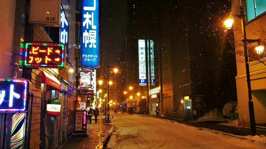 a snowy street at night with neon signs in the city