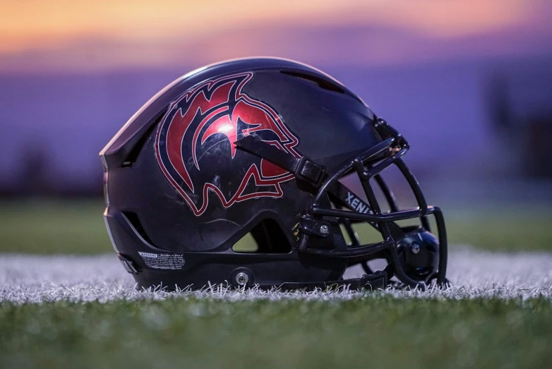 a helmet on the field with the sun setting