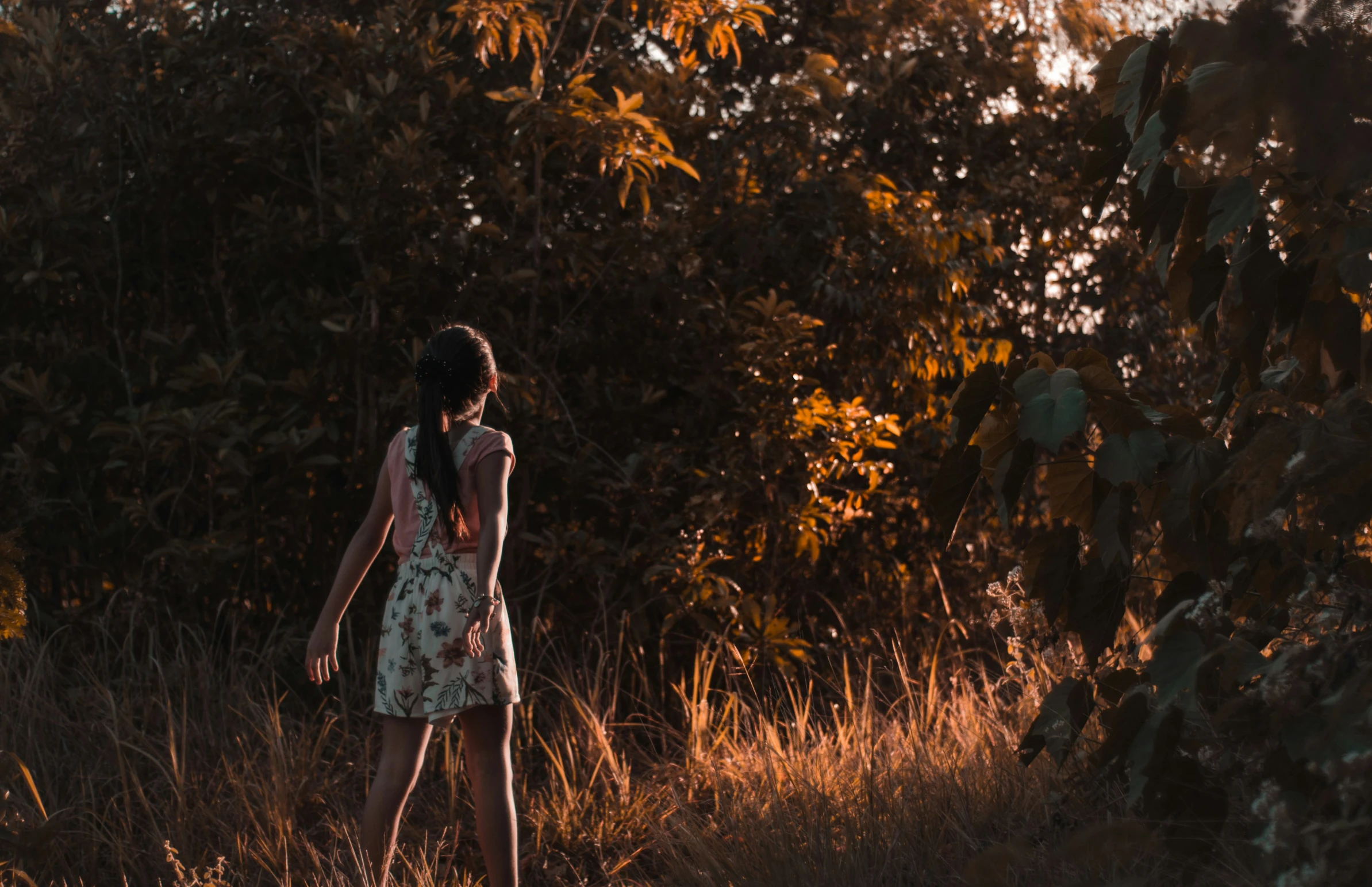 a girl is walking through a field looking for some flowers