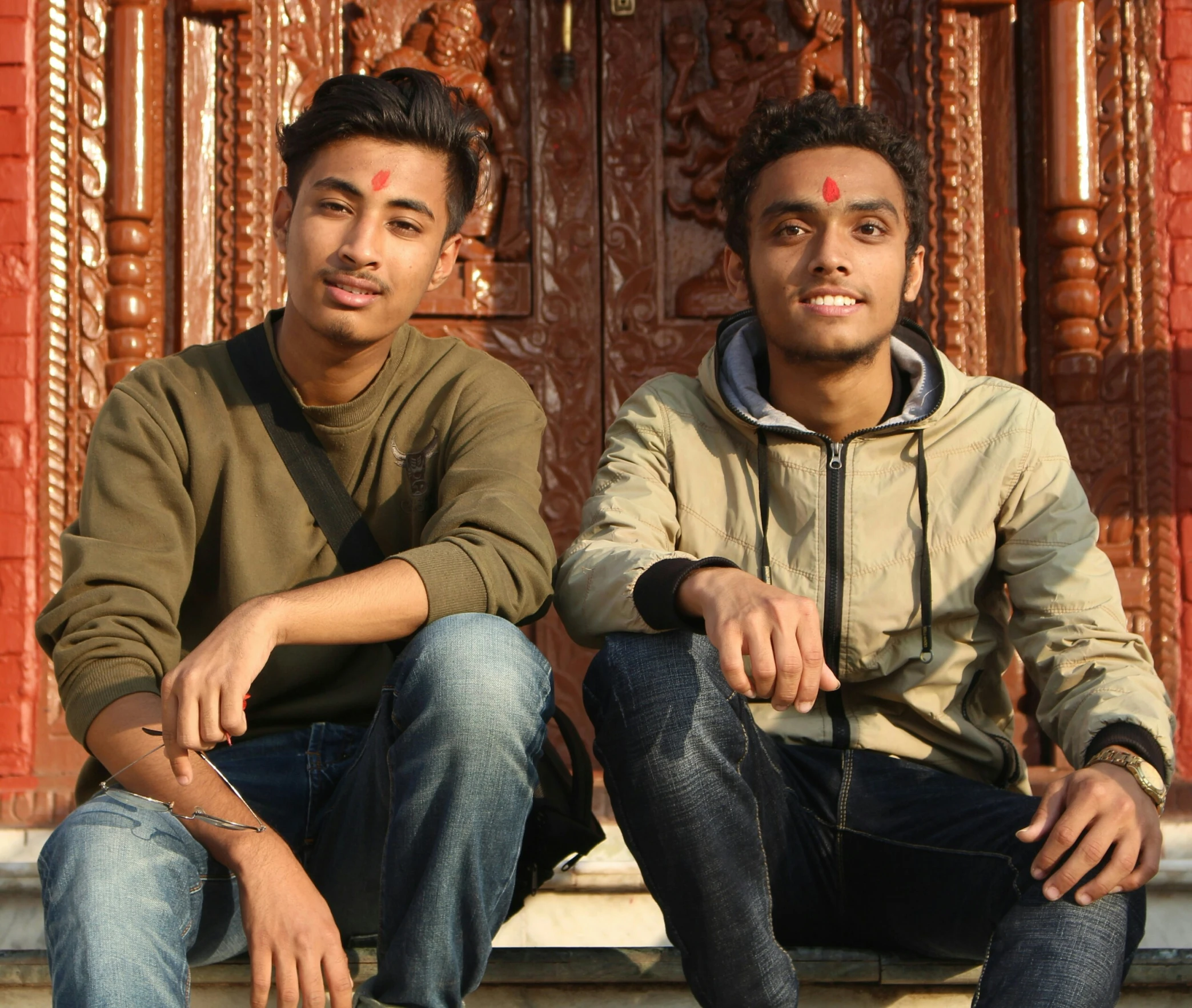 two men sitting down side by side in front of a doorway