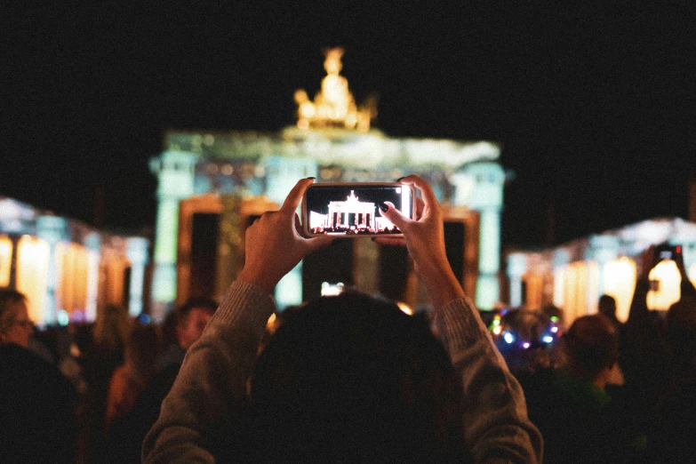 people taking pos with their cell phones in front of some buildings