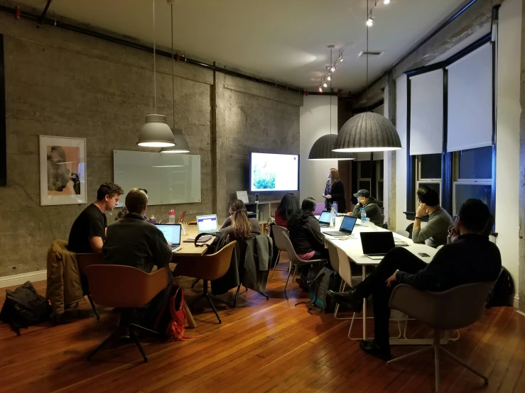 a bunch of people sitting at tables with laptops