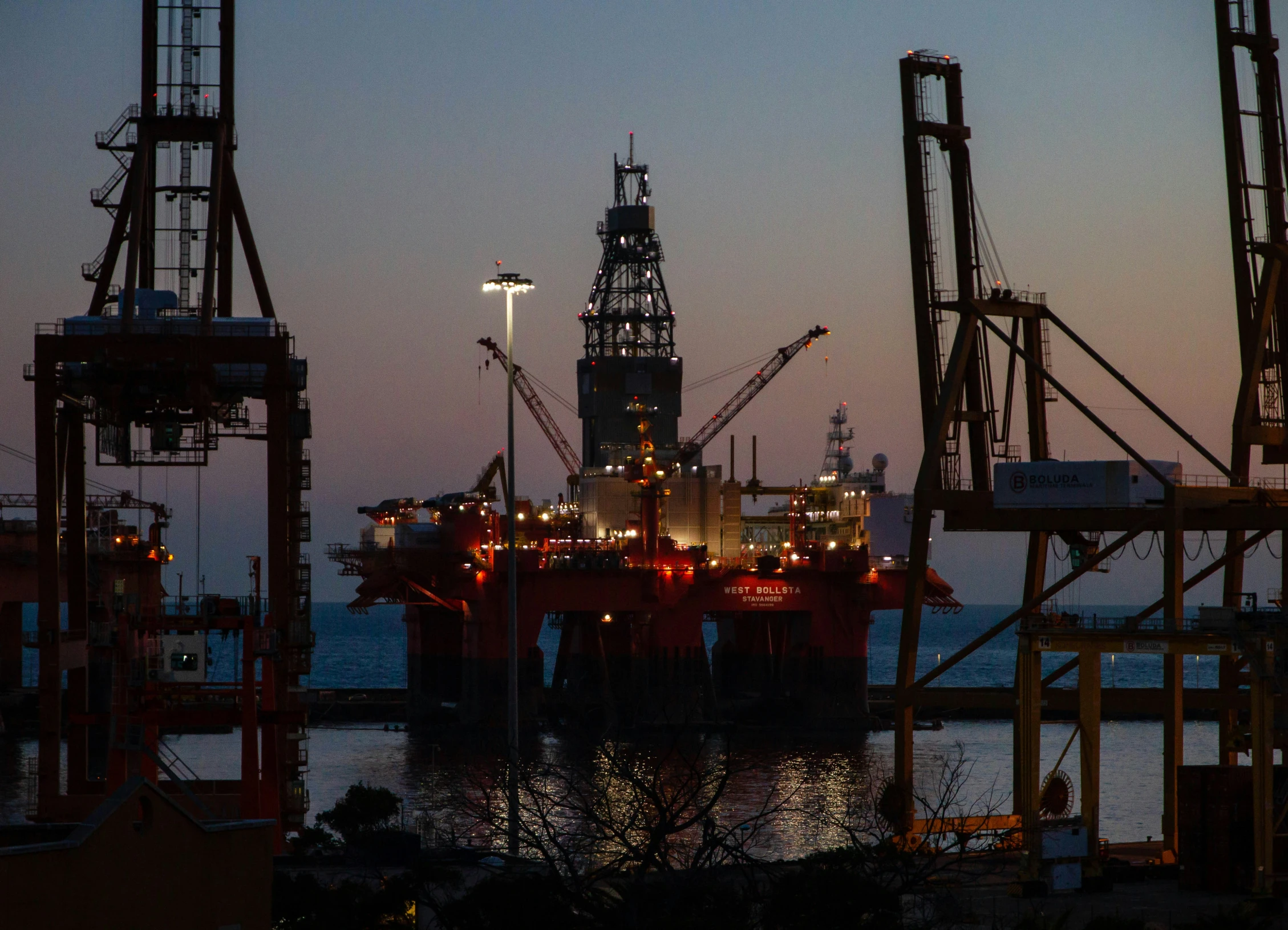 a cargo ship anchored at a dock in the evening