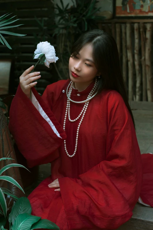 an asian woman wearing a long red dress with a flower