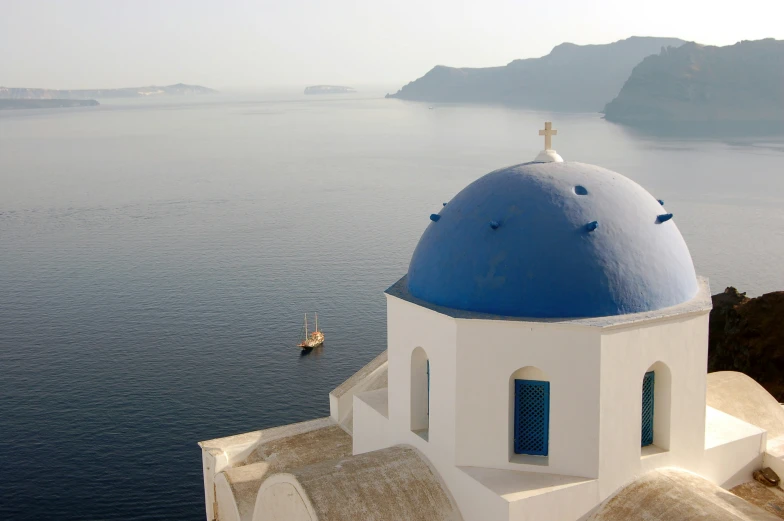 a small blue and white building with windows is on a hill side