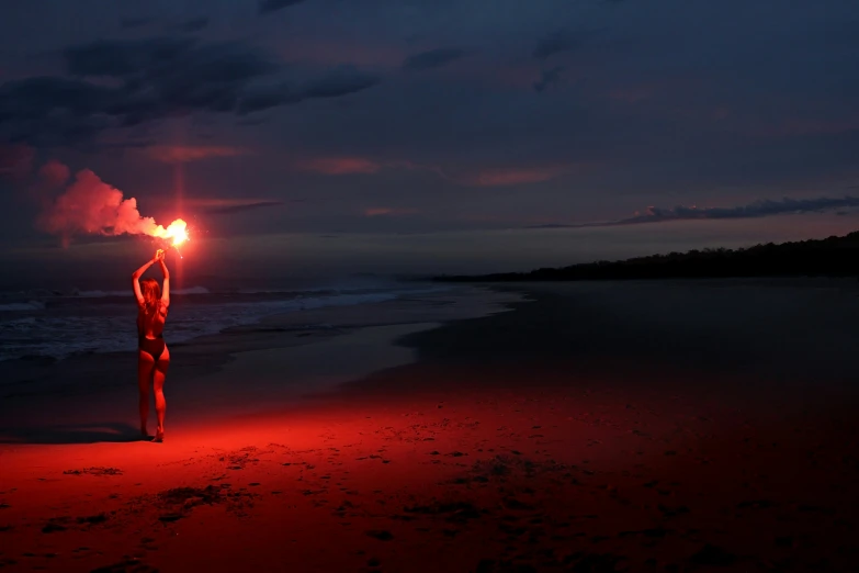 a man holding two flarers standing on a beach