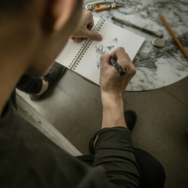 a person writing on a piece of paper on a table