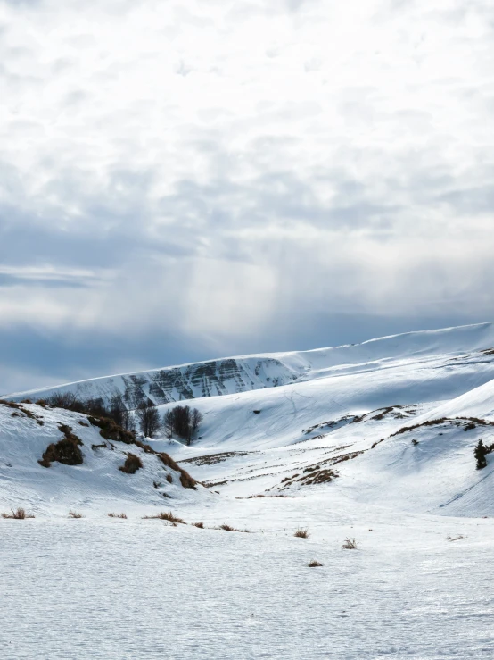 a snow covered mountain range with sky and clouds