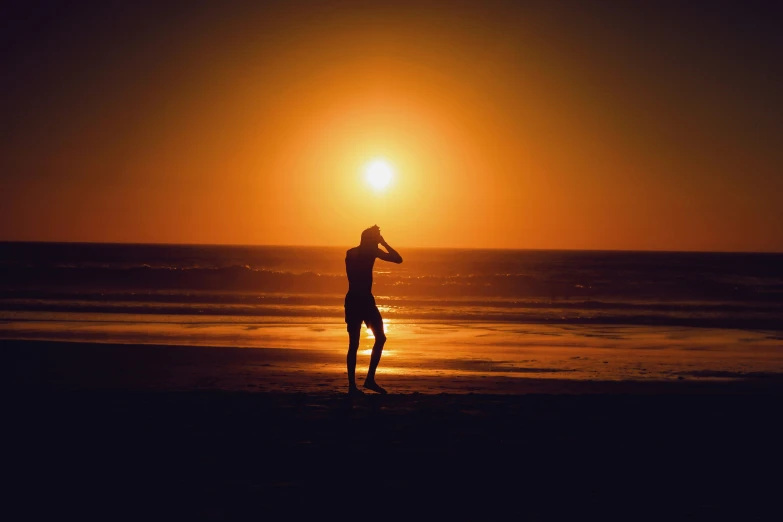 a person walking on the beach at sunset