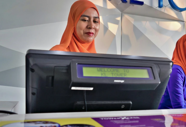 two women standing behind a counter with an electronic display in front