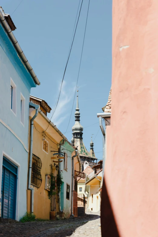 an alley way with some houses and a clock tower in the background