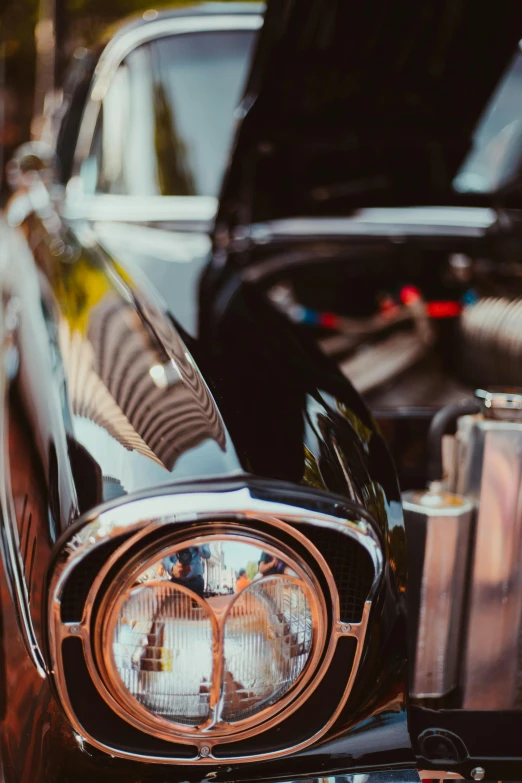 an old black sports car with the hood light on