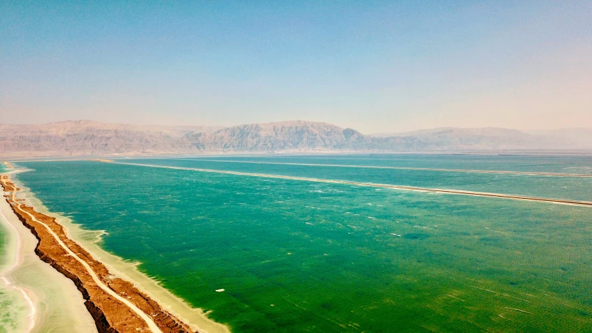 this is a long stretch of water that has a long stretch of sand, in between mountains and trees